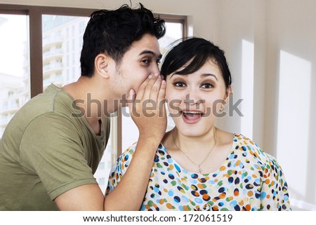 Portrait of a handsome young man whispering a secret to a cute woman