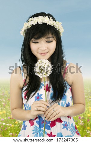 Beautiful woman with crown of flower is smelling flower