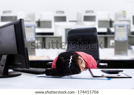Tired businesswoman sleeping on her desk in the office