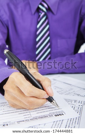 Closeup of businessman hand filling out a 1040 tax form