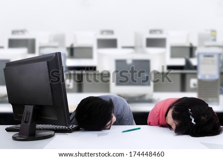 Two business people sleeping on the desk in office