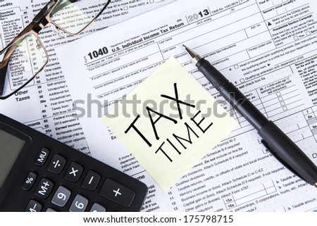 Tax forms with pen, calculator, glasses and sticker