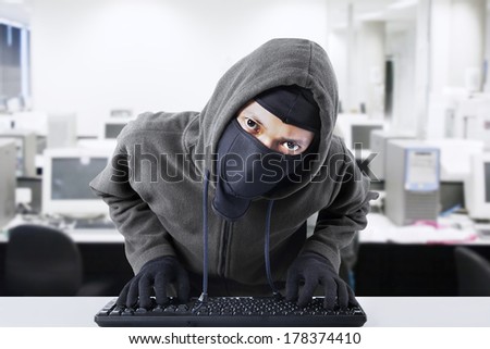 Computer hacker - Male thief stealing data from computer.  shot at office