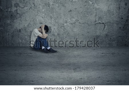 Young man sitting at the room corner with fear