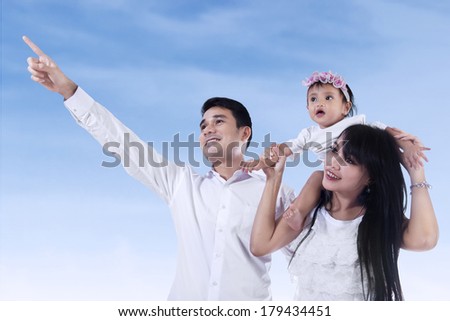 Young family pointing at copy space - shooting outdoor