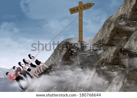 Portrait of business team climbing a success sign using rope on the mountain