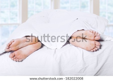 Close-up of couple\'s feet who had a fight on bed