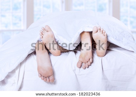 Close-up of couple\'s feet having intimate relation in bed