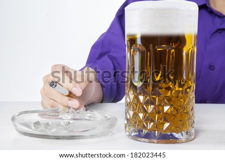 A man holding cigarette with a glass of beer