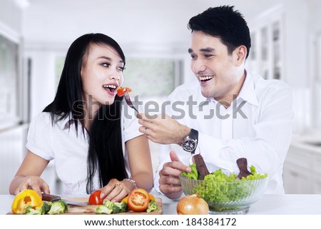 Happy couple making vegetables salad in the kitchen