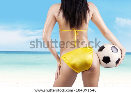 Backside sexy woman with a soccer ball at beach