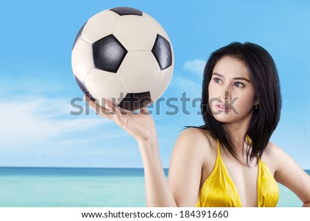 Young sexy woman holding a soccer ball at beach