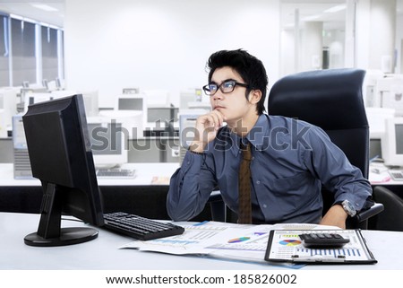 Pensive young businessman looking up with concentration