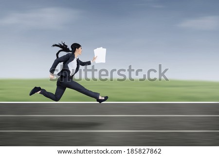 The young beautiful businesswoman runs by holding business paper