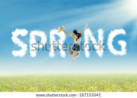 Young woman jumping with spring clouds on the park