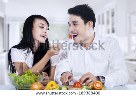 Happy couple preparing vegetable salad in their kitchen at home