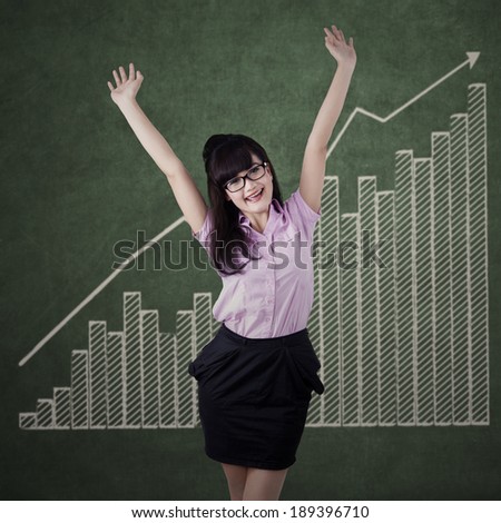 Portrait of cheerful businesswoman expressing success in front of business chart