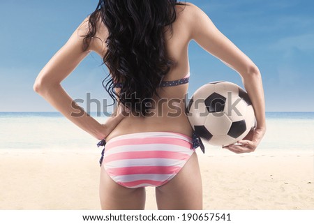 Backside sexy woman with a soccer ball at beach