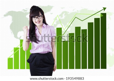 Successful young business woman happy for her success in front of a business graph
