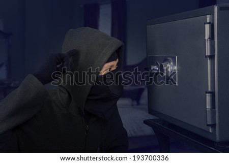 Portrait of confused robber trying to open a safety box