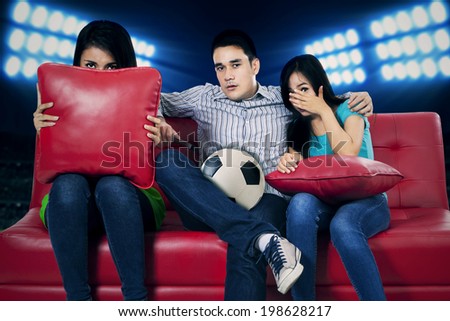 Soccer fans watching tv and showing fear expression for lose