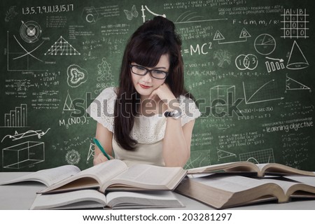 Female student studying at reading room while writing the source on book