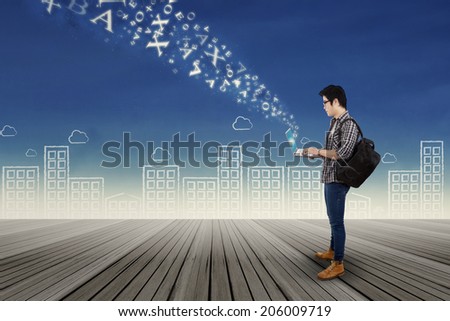 Portrait of young college student typing on laptop with flying letter from it