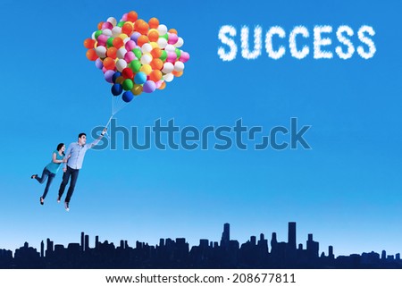 Happy couple flying with balloons to realize their dream