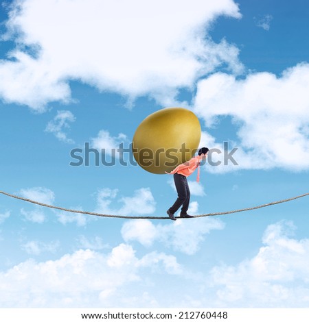 High investment risk concept: businessman carries a golden egg while walking on a rope