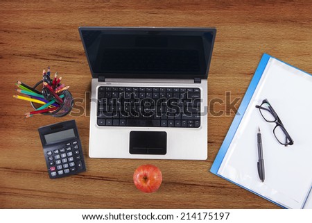 High angle view table of laptop computer, folder, glasses, pen, apple, and crayons