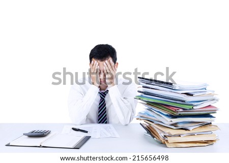 Young businessman overwhelmed with stack of files on the desk