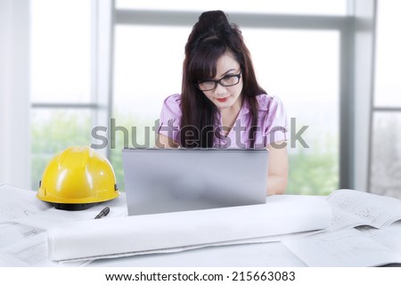 Portrait of young asian architect working at office with laptop and blueprint
