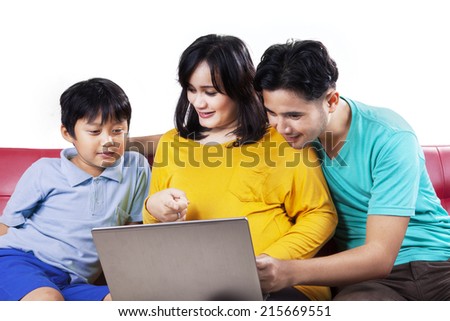 Pregnant mother and her husband teach their son with laptop, isolated over white background