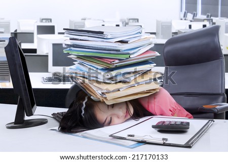 Asian secretary sleeping in office with paperwork on her head
