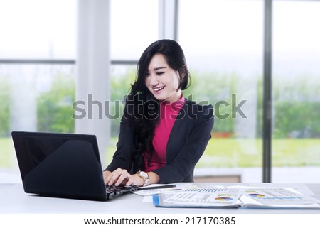 Happy business woman working on laptop computer at office
