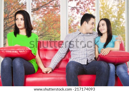 Young man hugging his girlfriend and holding hands his best friend with autumn background