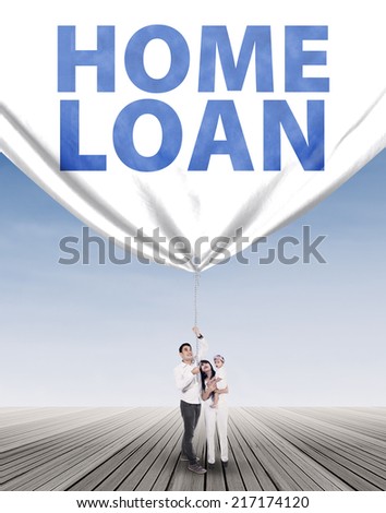 Full length of hispanic family pulling a home loan banner symbolizing their future plan