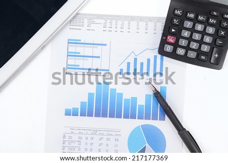 Modern business workplace with digital tablet, calculator, pen and printed data sheet