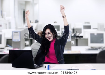 Successful asian businesswoman with arms up - shot in the office