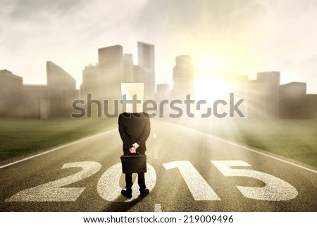 Businessman with cardboard head standing on the road and looking the future 2015