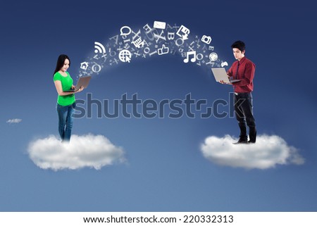 Two business people standing on cloud and use laptop computer to send information