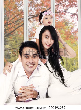 Happy family smiling at camera on bedroom with autumn background on the window