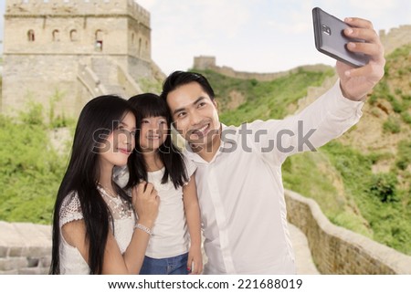 Three of member happy family taking self portrait together in Great Wall of China