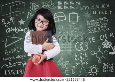 Learning concept with cute little girl holding a book and apple in class room