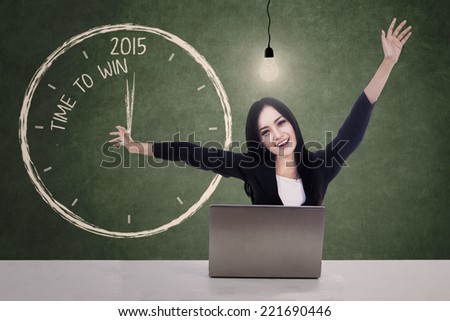 Cheerful beautiful woman with laptop, lightbulb, and celebrate time to win in 2015