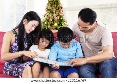 Happy family sitting on sofa while reading a story book at home