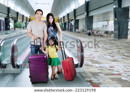 Happy family with luggage in holiday trip standing on airport hall
