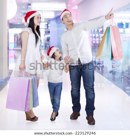 Happy family carrying shopping bags and looking at a store in the mall