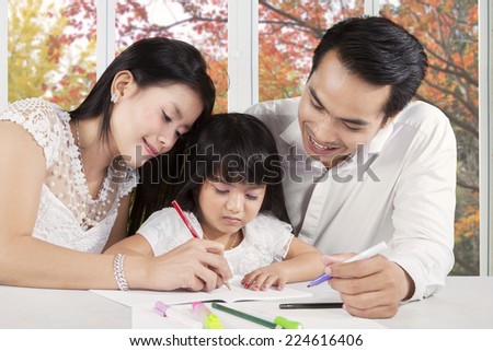 Portrait of two parents give homeschooling education to their child at home