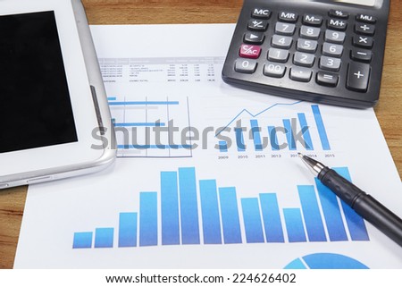 Printed data sheet with pen, calculator, and digital tablet on the table